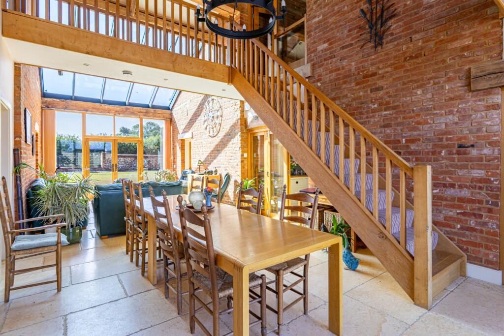 Double-height atrium with an oak staircase, brick walls and a glazed roof