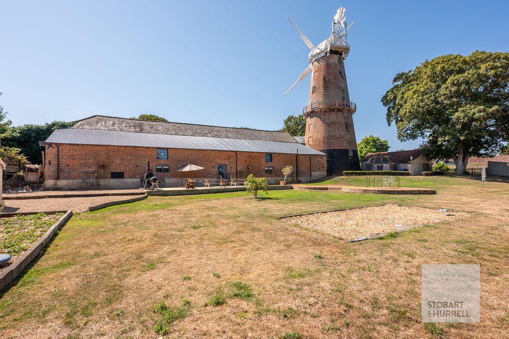 The long brick barn and windmill seen across the lawn
